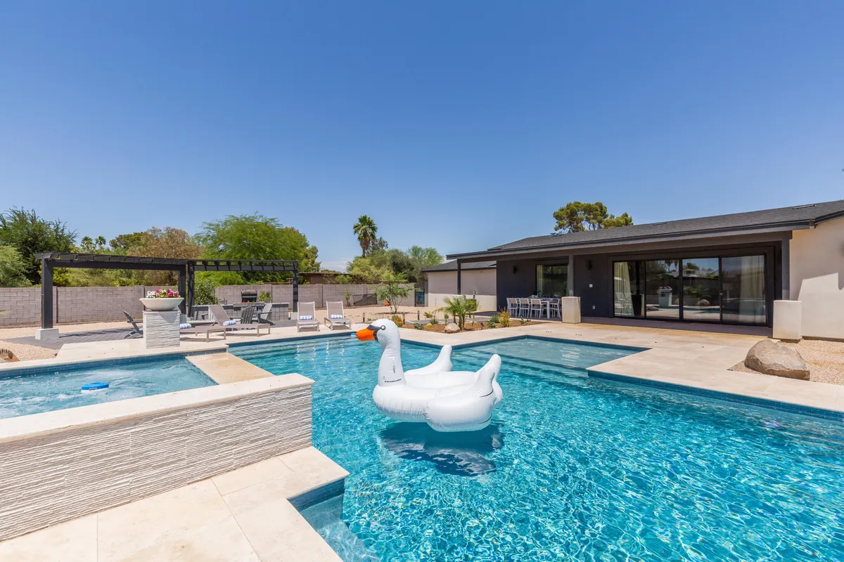 The hero image showcases a sparkling swimming pool at sunset, with an inviting inflatable swan floating on the water and a stylish outdoor seating area nearby. The scene radiates relaxation and fun, perfect for swimming, sunbathing, or gathering with friends and family against a beautiful Arizona backdrop.