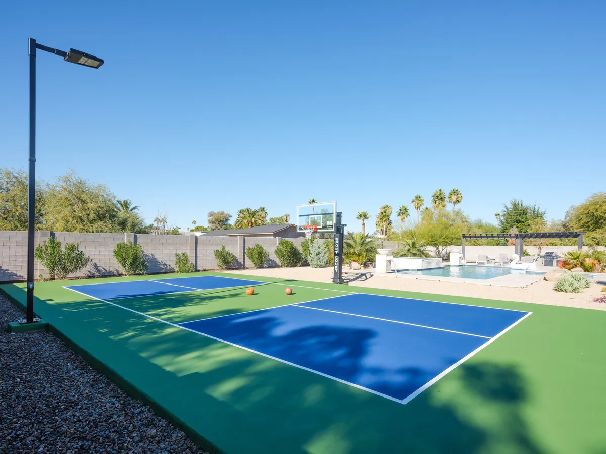 This exterior image captures a vibrant backyard scene featuring a basketball court with a hoop, palm trees, and a sparkling swimming pool. The setting exudes energy and encourages playful activities such as basketball games and poolside fun, with ample space for outdoor gatherings.