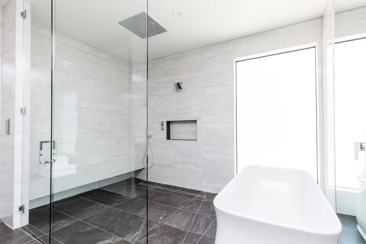 An elegant, spa-inspired bathroom with a glass shower enclosure, freestanding bathtub, and textured wall tiles, exuding a calming and luxurious atmosphere. This space invites guests to relax and refresh in privacy.