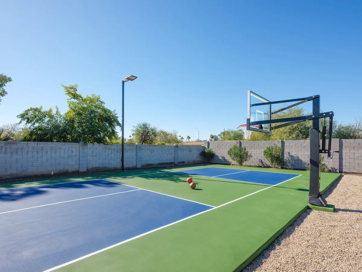 A vibrant, energetic backyard sports court with a basketball hoop, basketball, and surrounding greenery, ready for friendly tournaments and family activities.